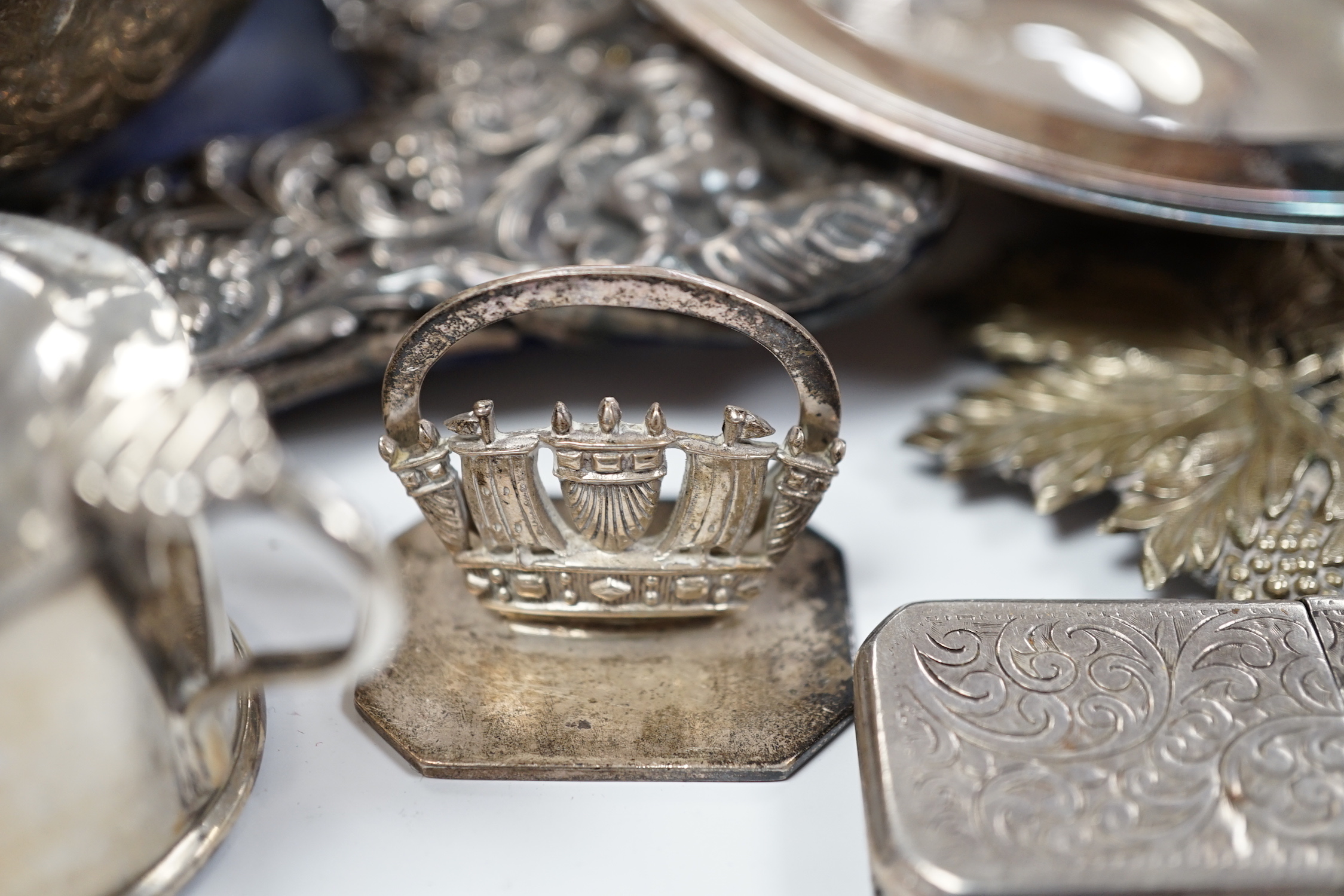 A quantity of silver items including a late Victorian repousse photograph frame, William Comyns, London, 1899, 20cm, three Georgian pepperettes, pair of small Armada dishes, quaich, vest case, menu holder, basting spoons